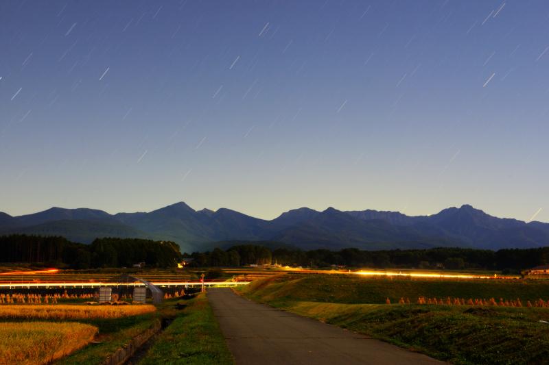 [ 星降る八ヶ岳 ]  原村の田園地帯からは八ヶ岳が一望できます。星空と車のライトで幻想的な風景に。