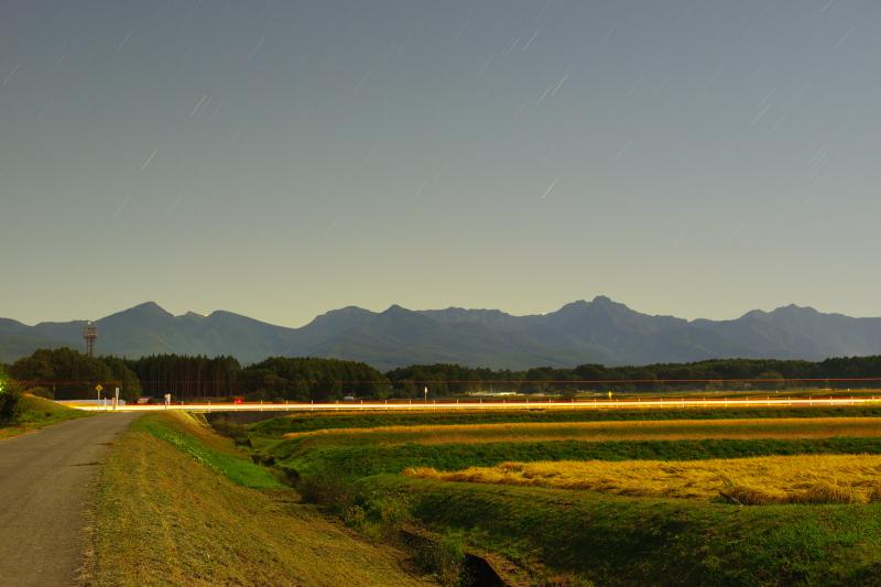 [ 月光に照らされた八ヶ岳 ]  月明かりを浴びた幻想的な八ヶ岳。八ヶ岳エコーラインを通る車のライトが一筋の光に。