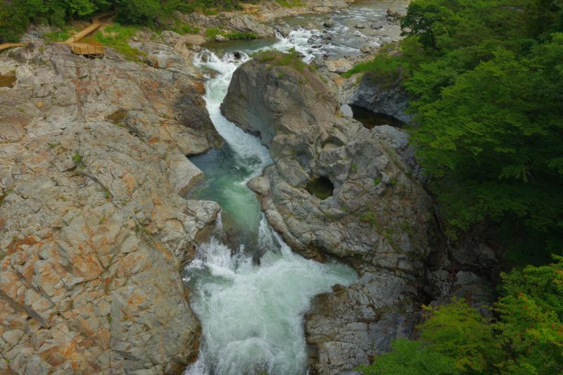 [ 峡谷俯瞰 ]  橋の上から展望台と巨大な岩を望む。丸い穴の空いた大きな岩は生き物のよう。