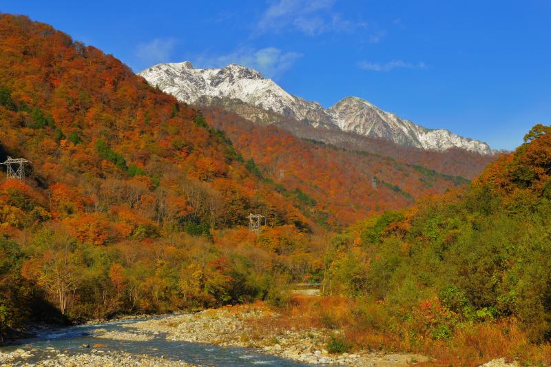 [ 谷川岳三段紅葉 ]  蛇行する湯檜曽川の流れ、一面に広がる紅葉、雪化粧した谷川連峰が美しい。