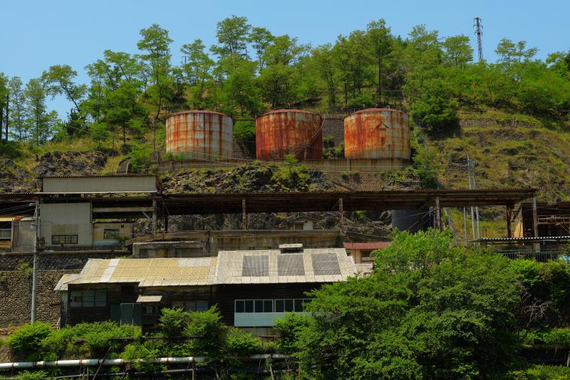 [ 3つの寂れたタンク ]  本山精錬所跡の3つのタンク。タンク下には駅のホームのような建物が見えます。