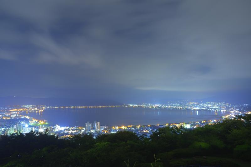 [ 真夜中の諏訪湖 ]  公園先端の柵付近から撮影しました。流れる雲が幻想的な夜でした。