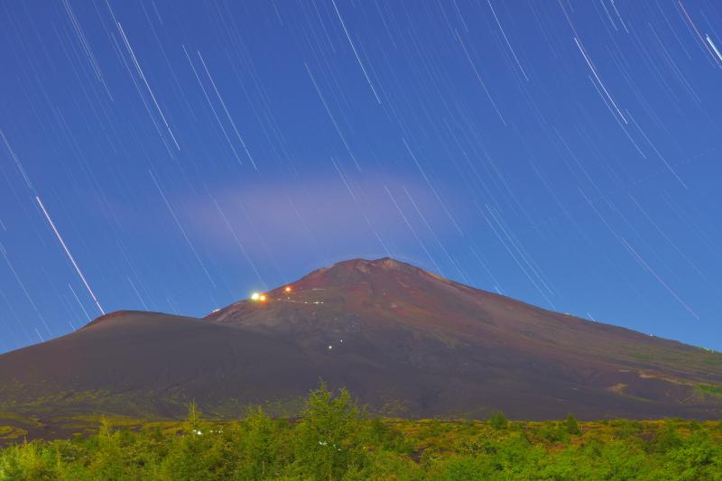 山小屋の灯と星| 月明かりに照らされた真夏の富士山。山小屋の灯りと登山客のヘッドランプが見えます。空には星が輝いていました。