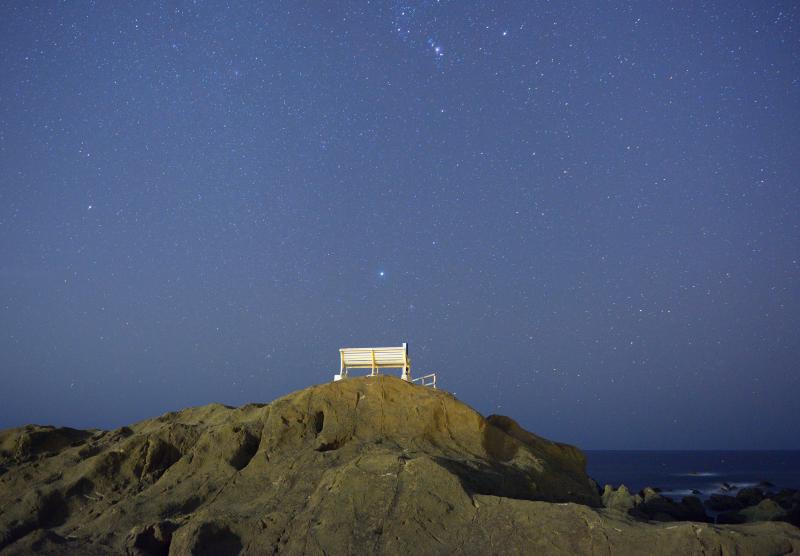 白いベンチと星空| 天の川撮影で人気の野島崎。大きな岩の上に白いベンチがあるという不思議な風景。