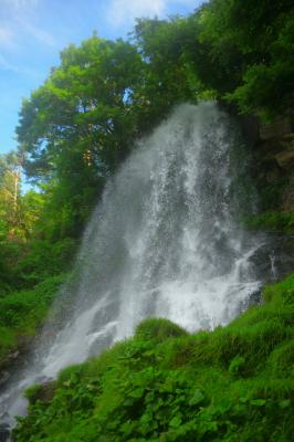 夏の青空と緑に映える滝。木々のフレームの中、真っ白い水しぶきが美しい。