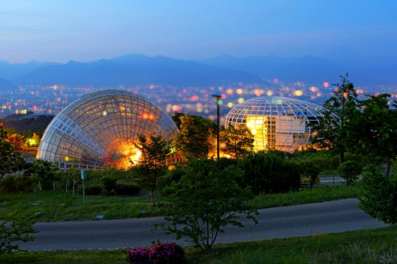 [ ドームと甲府盆地の夜景 ]  公園のシンボル的存在である２つのドーム。その奥には甲府盆地が広がっています。