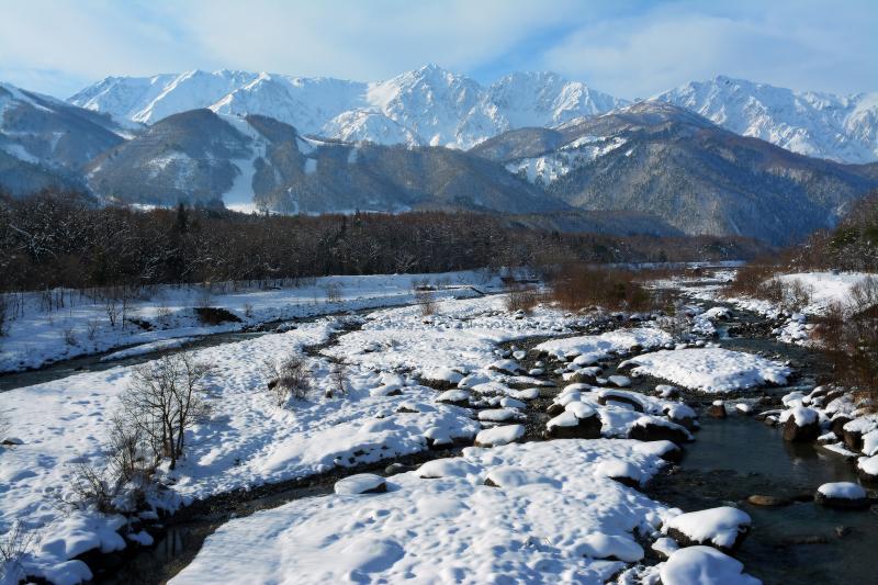 [ 白馬大橋から白馬三山を望む ]  北アルプスから流れる松川の河川敷は雪に覆われます。橋の北側に駐車スペースあり。冬季は雪捨て場になっており大型車に注意。