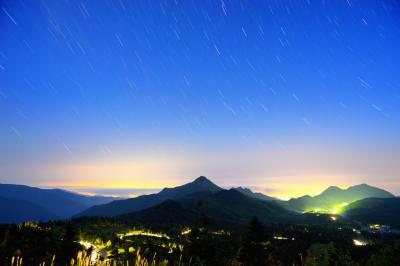 夜明け前の志賀高原横手山。次第に空が明るくなり夜空の星が消えていきます。国道292号を登ってくる車と、街灯りに照らされた雲海が輝いていました。